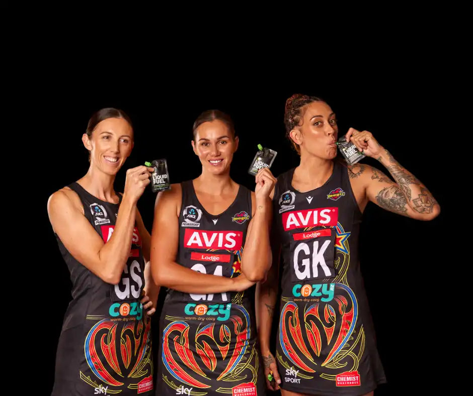 Three netball players holding drink pouches.